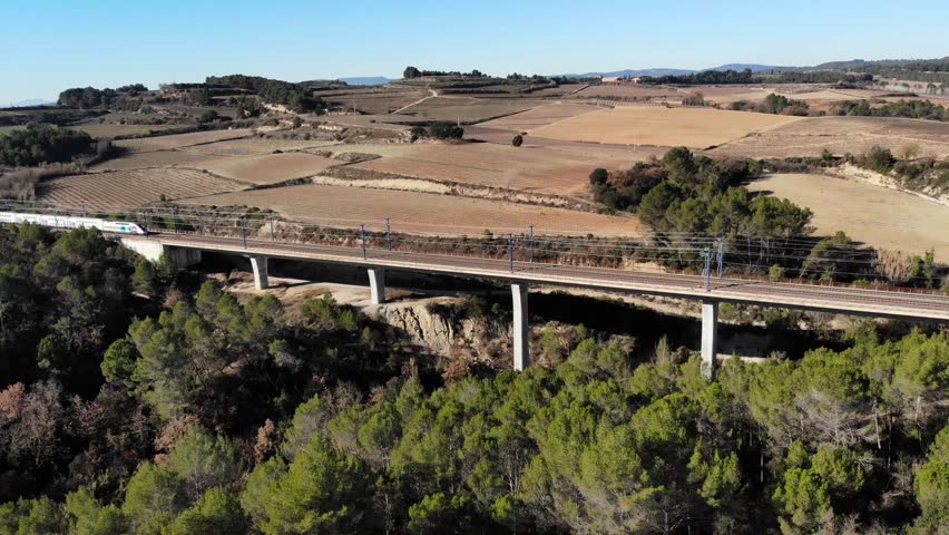 Aerial: double-decker high-speed train in Spain crossing a viaduct between Barcelona and Madrid, in Catalonia Royalty-Free Stock Footage #1098868653