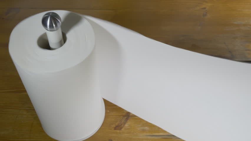 Closeup of soft, absorbent, white paper kitchen towel, being pulled from a new roll on an upright holder, on a pine kitchen worktop counter. | Shutterstock HD Video #1098869951