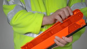 Closeup of a man wearing a fluorescent yellow, high visibility or hi vis or hi viz, fleece safety jacket, folding an orange, reflective warning triangle after use. - Powered by Shutterstock - Get 15% off with code: PIKWIZARD15