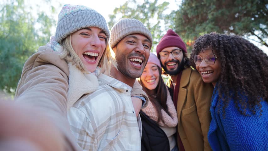 Group of young people smiling and having fun taking selfie portrait. Five multiracial happy friends looking at camera. Funny outdoor activity of cheerful students away from home. Lifetyle concept
