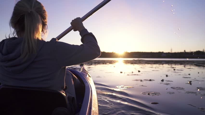 Oar paddles on calm water against the background of sunset rays