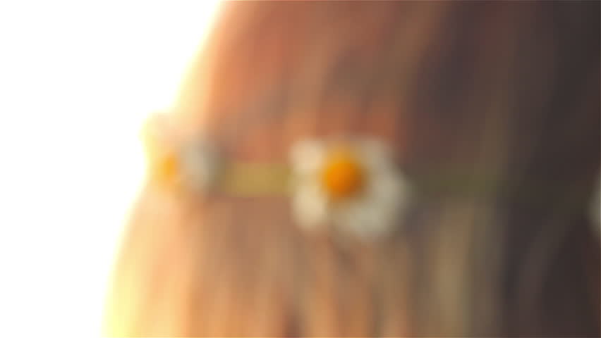 A young blonde girl wears a flower crown during golden hour.