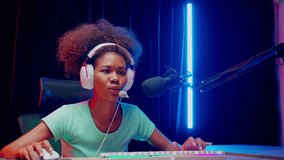 Young African American woman wearing headset play video game and live streaming online with microphone at home, gaming and esport or casting game, one person, broadcast and entertainment concept.
