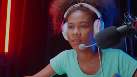 Young African American woman wearing headset play video game and live streaming online with microphone at home, gaming and esport for competition or casting game, broadcast and entertainment concept.