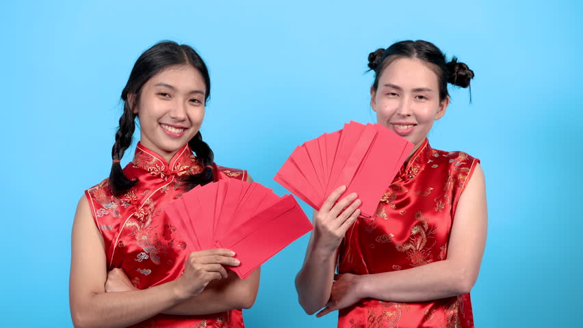 Asian pretty women in traditional red costume clothes happy show many ungpao in Chinese culture, young working girls receive surprise bonus or reward in red envelops, women shopping lifestyles concept