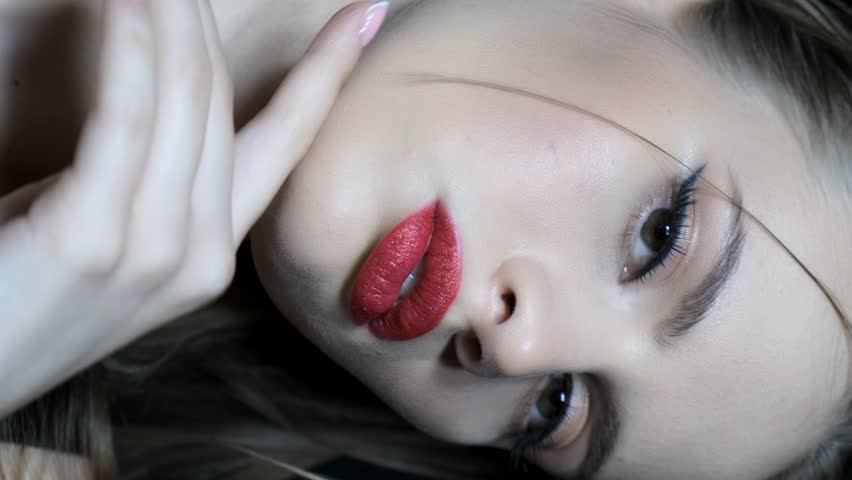 Slow motion vertical video of beautiful young woman face. Female with long earring with rhinestones is in the ear.