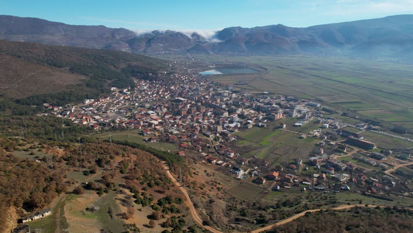 Perrenjas city residential houses built on edge of field and hills near reservoir in Albania