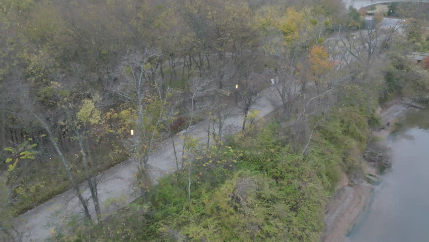 Aerial footage following a person riding their bike on the sidewalk next to the Tennessee River in Coolidge Park.