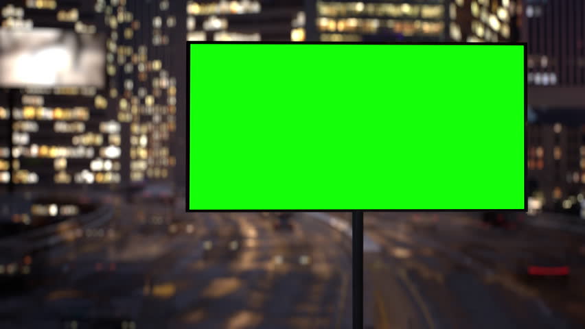 Large billboard with a green screen on a busy highway with traffic, neon lights, modern buildings at background. Blank billboard for advertising. Timelapse at night