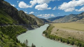 Video of Altai natural landscape with river Katun under blue sky with clouds. On the left bank of the river there is Chuya Highway, one of the most beautiful roads in the World.
