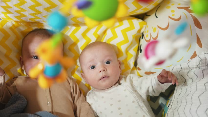 two twins lie in a bed. happy family kid dream concept. cute twins lie in bed in the bedroom in the evening smile look at the toy. newborn lifestyle boy and girl brother and sister