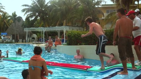 CAYO COCO, CUBA - JUNE, 2011: A resort entertainment director emcees as young Canadian tourists play games at a swimming pool.