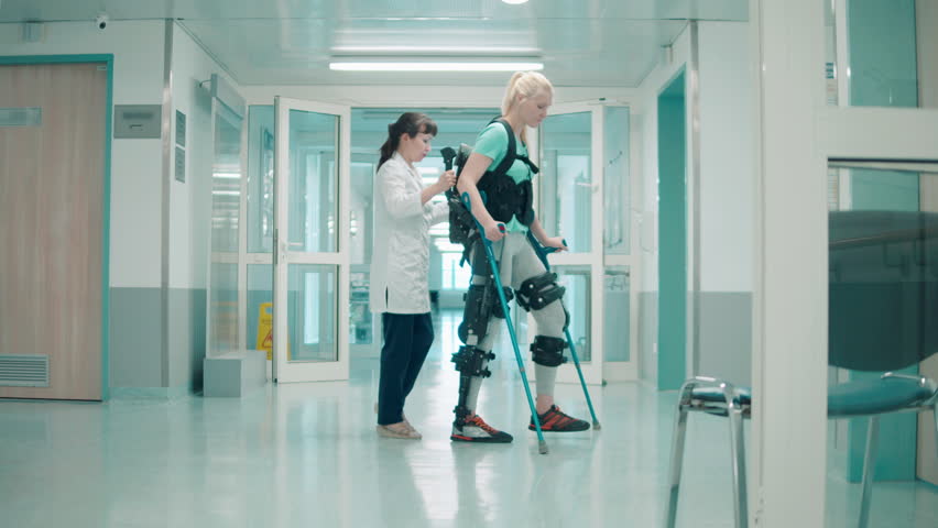 Doctor is helping a handicapped woman to move in the exosuit Royalty-Free Stock Footage #1098897633