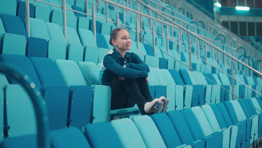 Female figure skater on the seats of the sports arena