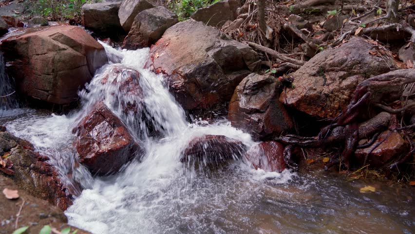 Stream with clear water runs down the mountainside, giving coolness and freshness to the vegetation around. At the end of the path, slowing down and falling into the lake at the foot of the rocks.