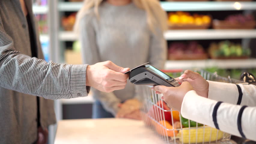 Unrecognizable female shopkeeper cashier using a wireless credit card reader. | Shutterstock HD Video #1098901659
