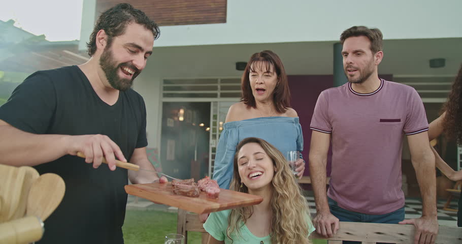 Brazilian barbecue. Person serving food to group of friends at home backyard BBQ celebrating life with family | Shutterstock HD Video #1098901853