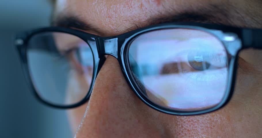 Close up male eyes in eyeglasses working late at night scrolling internet pages in front of laptop computer at home. Macro portrait of male in glasses with reflection of computer screen working online Royalty-Free Stock Footage #1098902091