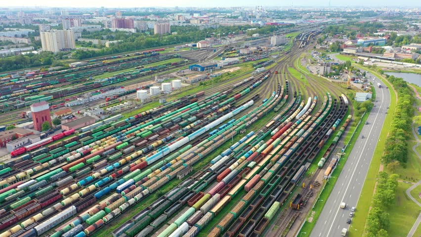 Panoramic aerial view of a large sorting marshalling yard railway station with many freight trains against the backdrop of the urban landscape Royalty-Free Stock Footage #1098903573