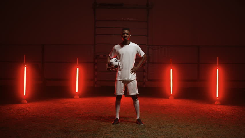 Portrait of African ethnic footballer in white uniform looking at camera, national team player 