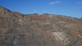 Camera flying up forward from industrial open pit to windmill wind turbine generators on a hill. environmental problems and its solutions. Aerial drone video. Murcia region, Spain