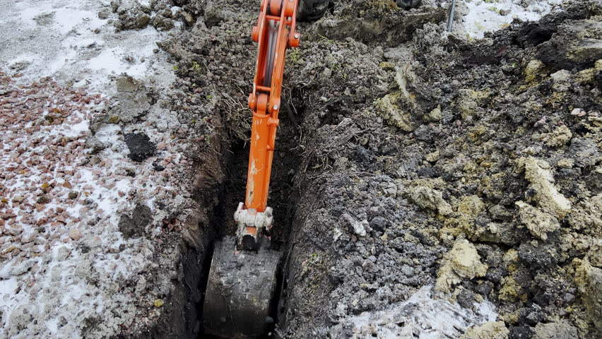 Close up shot footage of A bucket of the excavator getting soil from the ground during the winter time. 