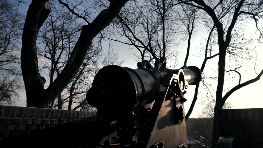 Camera movement around an old powder cannon. Medieval weapons in a tourist place in a city park during sunset. The sunbeam shines into the lens. Artillery piece of the 17th or 16th century, field gun.