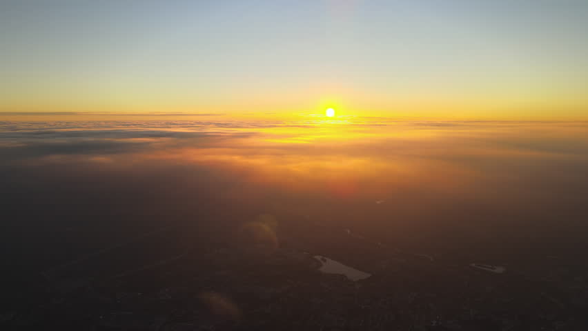 Aerial view from airplane window at high altitude of distant city covered with layer of thin misty smog and distant clouds in evening Royalty-Free Stock Footage #1098912703