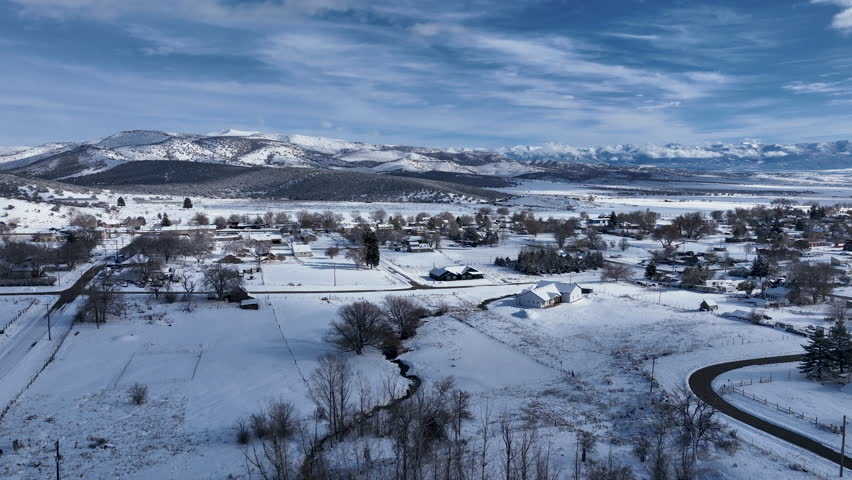 Aerial winter snow valley rural town 1. Rural farming community agricultural economy. Homes and traffic on highway Main Street. Mountain valley winter snow. Seasonal snowy city.