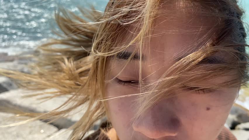 Beautiful asian woman portrait wear wireless earphone looking at sea close up shot outdoor windy day hair flapping ocean view background sunny day, Thailand