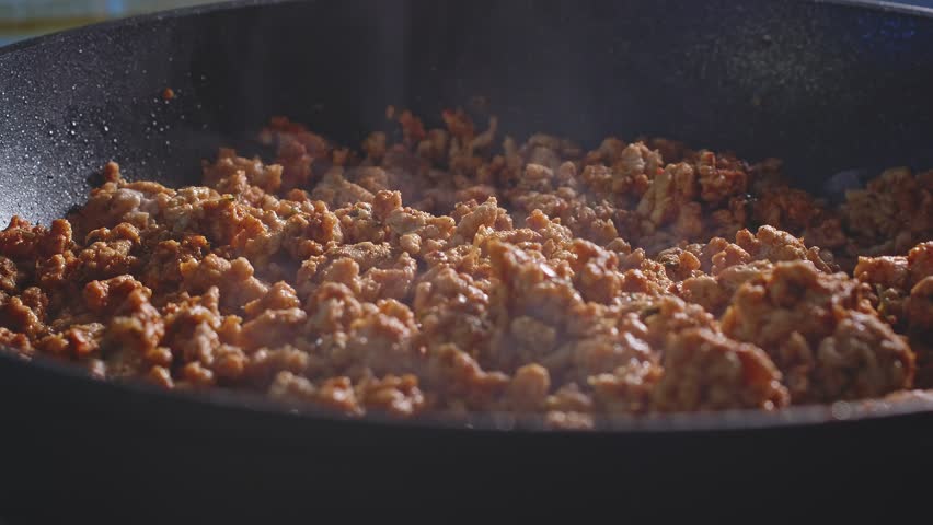 Adding Chopped White Onion, Red Bell Pepper, And Salt Into Ground Turkey Meat Cooking In Pan. closeup