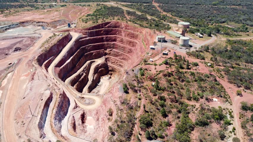 Aerial drone mining pit open cut copper ore mine with water tank bushland red rock travel industry tourism Fort Bourke Hill Cobar NSW Australia outback 4K