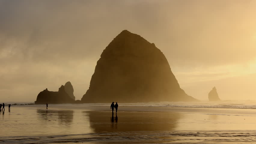 People enjoying beautiful sunset over Oregon coastline. Cinematic landscape of idyllic Cannon Beach with low tides crashing against the shore. High quality 4k footage Royalty-Free Stock Footage #1098923929