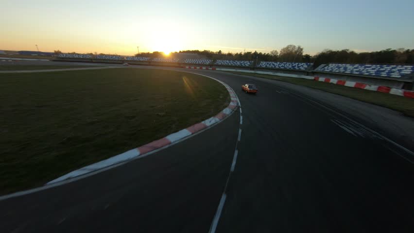 aerial filming of a circuit race on an asphalt circuit, fpv drone, racing cars go fast, time trials, sharp turns