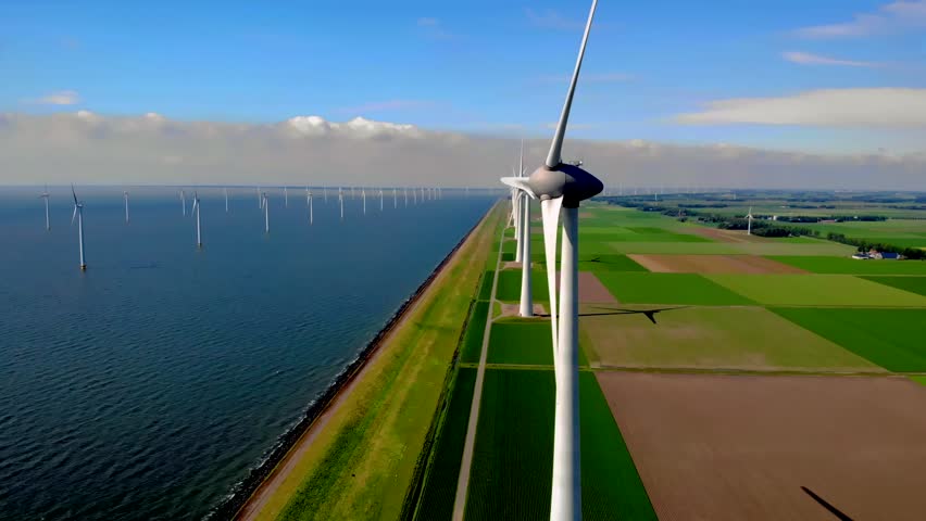 Offshore windmill park with clouds and a blue sky, windmill park in the ocean aerial view of wind turbine Flevoland Netherlands Ijsselmeer. Green energy.  Royalty-Free Stock Footage #1098930883