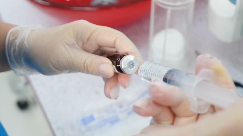 Professional cosmetologist getting ready for invasive procedure filling syringe with transparent liquid. Before beauty injection treatment. Doctor cosmetologist holding syringe in gloved hands | Shutterstock HD Video #1098933191