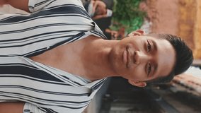 VERTICAL VIDEO: Young man looking at the camera and smiling
