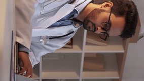 Vertical video. Male doctor. Doctoral thesis. Educational research. Smart man typing scrolling laptop sitting desk light room interior. - Powered by Shutterstock - Get 15% off with code: PIKWIZARD15