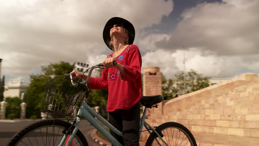 Portrait of smiling, happy, fun mature elderly woman in ethnic clothing having fun biking on vacation in front of the Monumento a la Patria monument in Merida, Yucatan, Mexico.