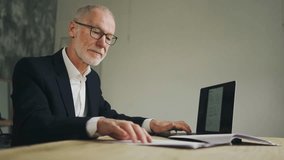 Old businessman is typing, Working with documents and a laptop. Verifies data. - Powered by Shutterstock - Get 15% off with code: PIKWIZARD15
