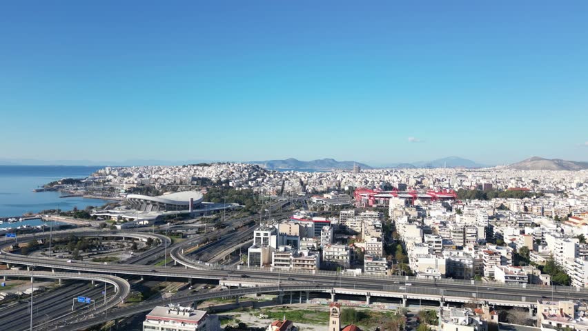 Aerial view video taken by drone of Piraeus Greece and urban motorway with the famous stadiums of Olympiakos known as Karaiskaki stadium and Peace and friendship stadium, Peiraeus, Attica, Greece