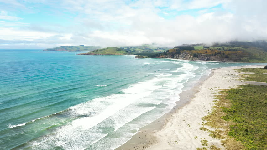Blue ocean waves of Blueskin Bay in Warrington domain beach, New Zealand, aerial view