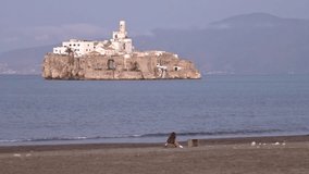Woman enjoying a warm day in the beach of Al Hoceima, Morocco, with the spanish military island of Alhucemas in front. - Powered by Shutterstock - Get 15% off with code: PIKWIZARD15