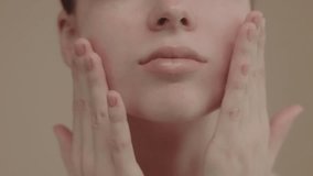 Extreme closeup feminine lips and chin applying anti aging cream on face skin. Women demonstrate moisturizing facial care touching cheek isolated in studio yellow background. 4k slow motion. - Powered by Shutterstock - Get 15% off with code: PIKWIZARD15