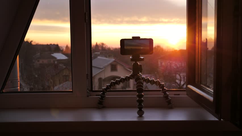 Capturing the sunrise with a cell phone camera.Shooting travel video on mobile phone camera on tripod, shooting cityscape in the morning during sunrise