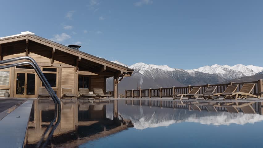 Raising shot swimming pool water with chaise longue wooden bathhouse spa resort exterior autumn landscape aerial view. Comfortable rural homestead bungalow health serpentine road infrastructure 4k