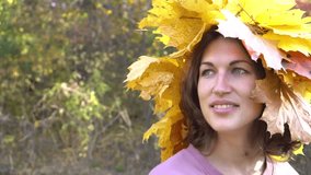 Beautiful girl in a wreath of yellow leaves on the background of an autumn park.