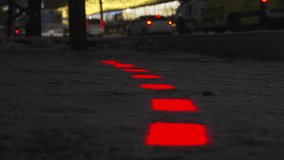 New modern traffic lights built-in and glow in sidewalk for pedestrians with phones in front of pedestrian crossing. Crowd of people crosses road in winter into snow. Luminous tiles . - Powered by Shutterstock - Get 15% off with code: PIKWIZARD15