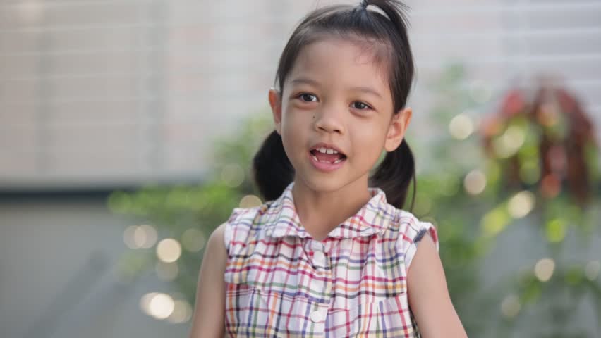Portrait of an Asian Thai kid girl with fresh and cute face aged 6 to 8 years old, strong and healthy. Showing a happy and fun dance. smiling face She is happily playing on vacation. Blur background | Shutterstock HD Video #1098961981