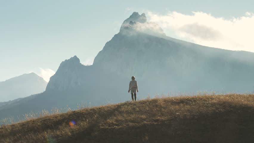 A male silhouette appears against the background of a mountain peak. The concept of calm unemotional achievement of the result. Enjoy the tranquility.